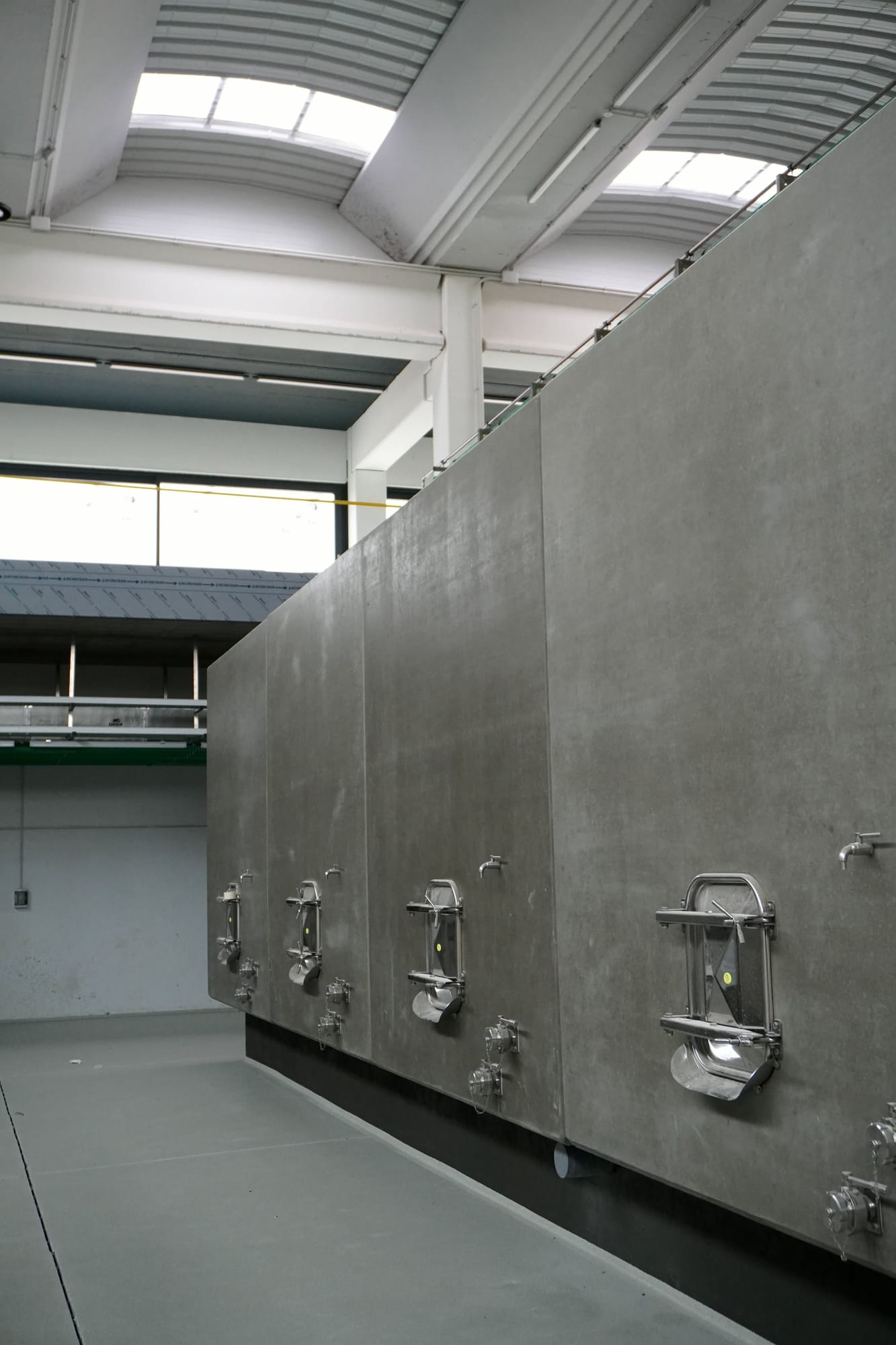 Muro de depósitos de hormigón con bocas de acero inoxidable en una nave